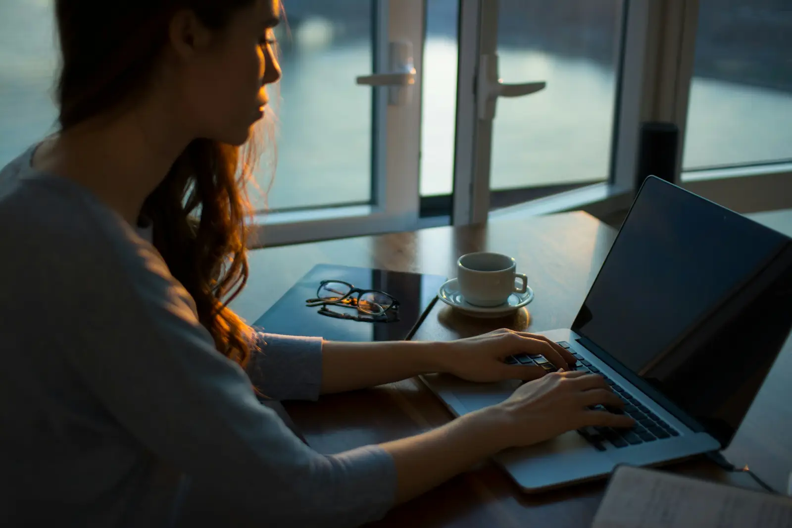 Une femme travaille sur son ordinateur portable, un café à côté d'elle