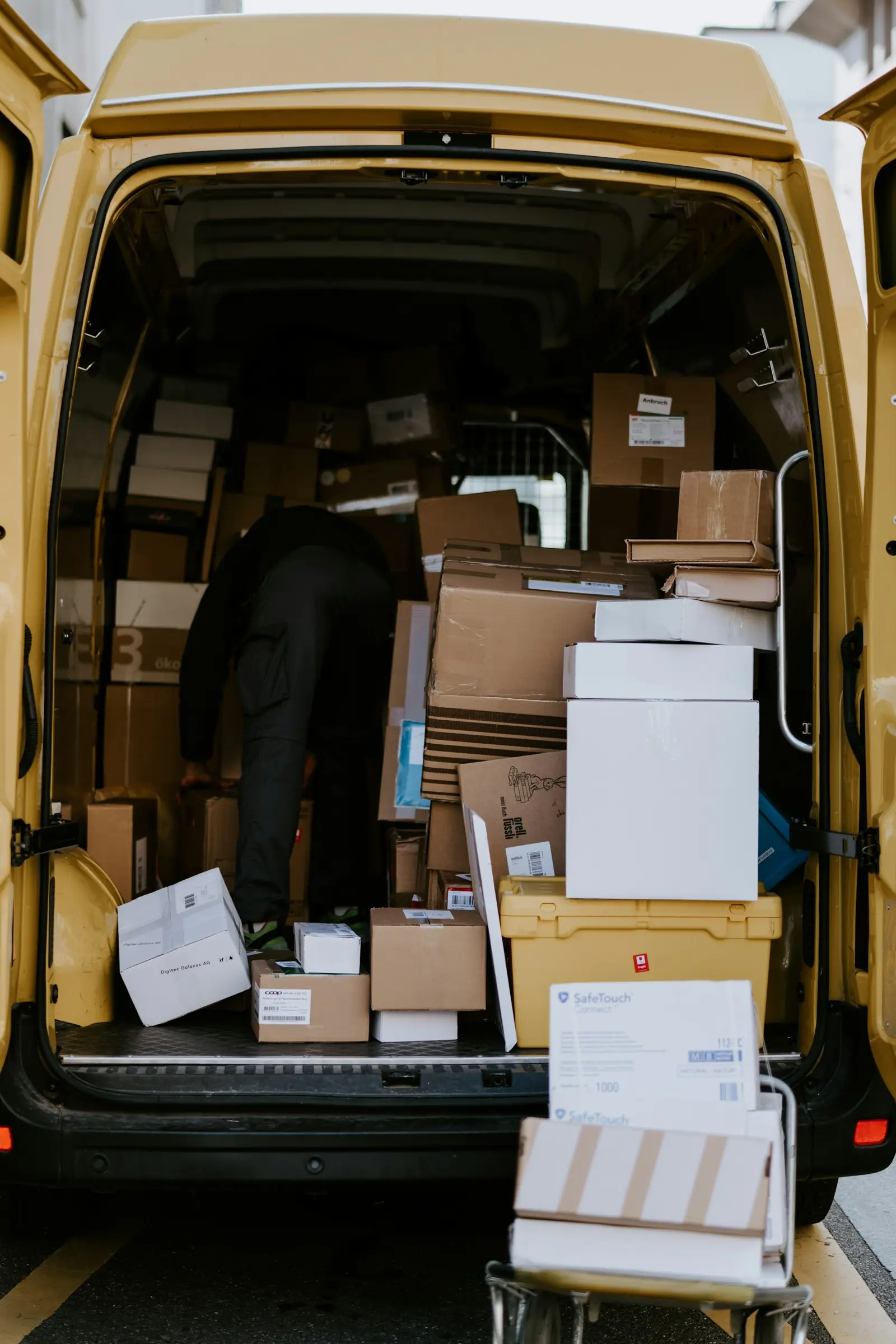 Un livreur charge des cartons dans un fourgon jaune