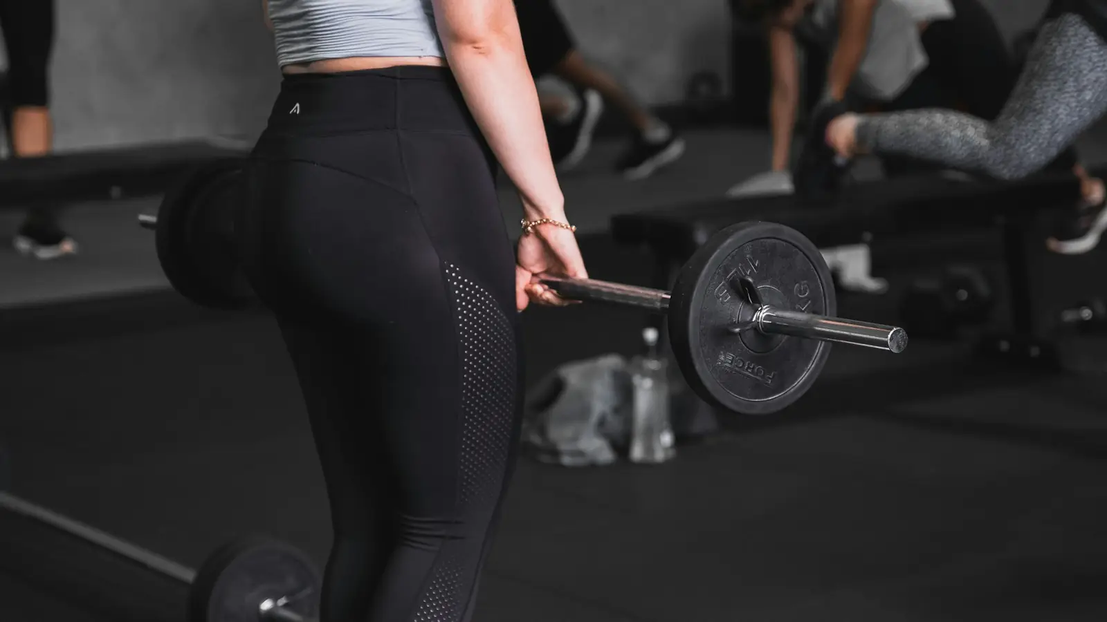 Une femme soulève une barre dans une salle de sport