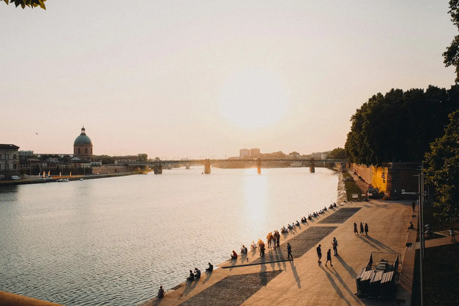 Des gens assis au bord de l'eau à Toulouse, au coucher du soleil